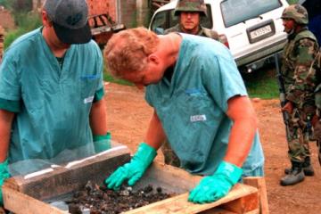 Investigators from the Royal Canadian Mounted Police Forensics Team sift through remains at a grave site in a village in Kosovo on July 1, 1999.